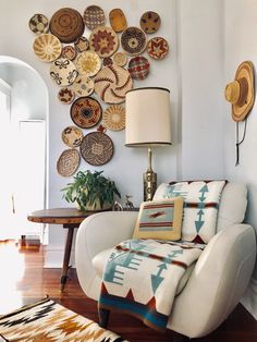 a living room with a white chair and many plates on the wall above it's head