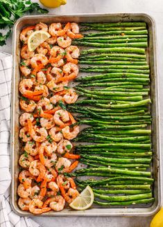 shrimp and asparagus on a sheet pan with lemon wedges