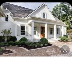 a white house with red door and brick walkway leading up to the front entrance area