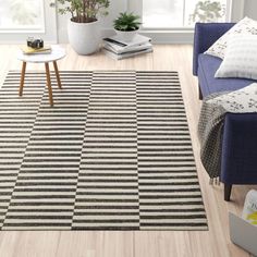 a living room with a blue couch and striped rug on the floor, next to a coffee table