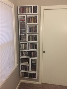 a white bookcase filled with lots of movies and dvds in front of a door