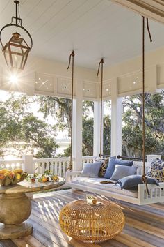 the porch is decorated with blue and white pillows, wicker furniture, and hanging lights