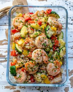 a glass dish filled with shrimp, zucchini and veggies