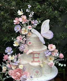 a three tiered cake decorated with flowers and butterflies