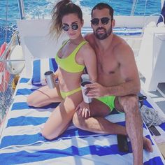 a man and woman in bikinis sitting on a sailboat with the ocean behind them