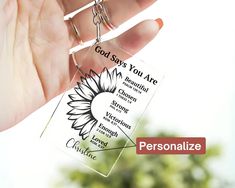 a person holding a keychain with the words god says you are surrounded by sunflowers