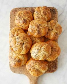 a wooden cutting board topped with rolls covered in powdered sugar on top of a marble counter