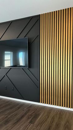 an empty room with a television mounted on the wall and wood flooring in front of it