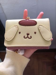 a person holding up a small purse with a cat face on the front and side