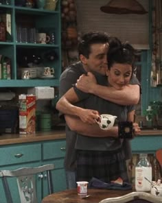 a man and woman hug in the kitchen while they are holding each other's arms