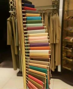 a rack with many different colored fabrics hanging on it's sides in a store