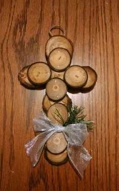 a cross made out of candles on top of a wooden table next to a bow