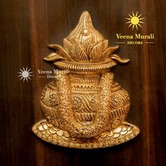 an intricately designed brass statue on a wooden surface with the words veena muraii decors above it