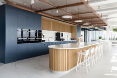 an open kitchen with blue cabinets and white counter tops, along with bar stools