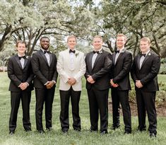 a group of men standing next to each other in tuxedos