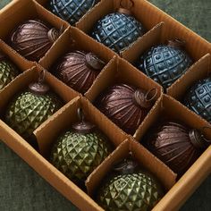 twelve decorative ornaments are in a box on the floor, including one green and one brown ornament