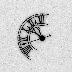 a black and white clock with roman numerals on the side of a wall