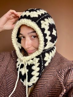 a woman wearing a black and white knitted hat with a hood on her head