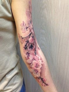 a woman's arm with pink flowers on it and butterflies in the middle of her arm