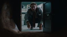 a man in a dark room with his hands on the ground looking into a door