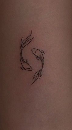 a woman's thigh with a small tattoo of two goldfish on the side