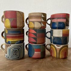 five coffee mugs are stacked on top of each other in different colors and shapes