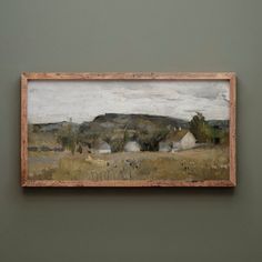 a painting hanging on the wall in front of a green wall with a brown frame