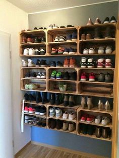 a room filled with lots of wooden shelves and shoes on top of each shelf in front of a door