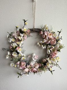 a wreath hanging on the wall with flowers and an elephant figurine in it