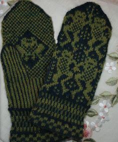 two green mittens sitting on top of a white cloth covered in leaves and flowers