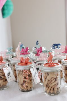 there are many small jars with different types of cookies in them and some decorations on the table