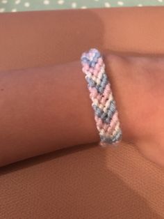 a woman's arm with a pink and blue braided bracelet on her wrist