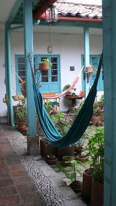 a hammock hanging from the side of a building next to potted plants