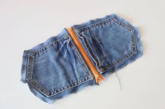 an old pair of blue jeans with orange zippers are laying on top of each other