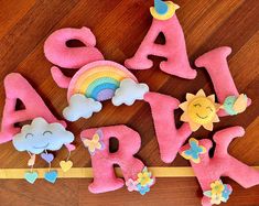 the letters are made out of felt and have rainbows, clouds, and sun on them