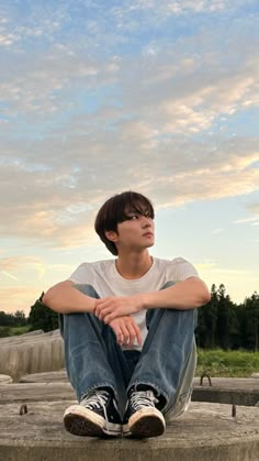 a young man sitting on top of cement steps with his arms crossed and looking up at the sky