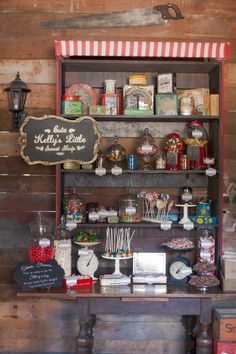 a shelf filled with lots of candy on top of a wooden table next to a sign