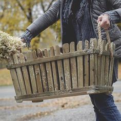 a woman carrying a wooden basket full of flowers