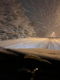 a car driving down a snow covered road at night