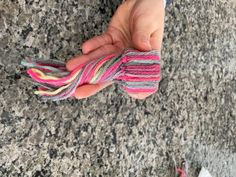 a person holding something in their hand on top of a granite flooring surface with pink, grey and yellow strips