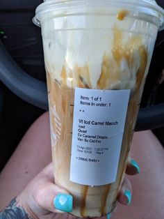 a woman holding up a cup with ice cream and caramel on it's side