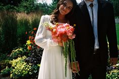 a man and woman standing next to each other in front of flowers