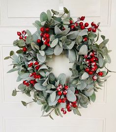 a wreath with red berries and green leaves hangs on the front door's side