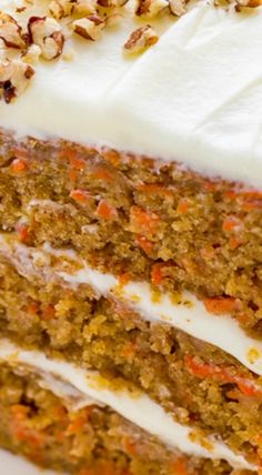 carrot cake with white frosting and nuts on top