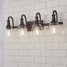 three light bathroom fixture with clear glass shades on the top and bottom lights in an old - fashioned style