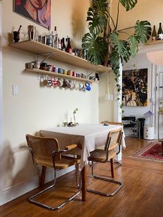 a dining room table with two chairs and a potted plant on the wall above it