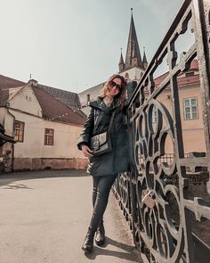 a woman leaning on a gate in front of some buildings