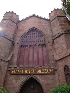 the entrance to salem witch museum is surrounded by greenery and brick buildings with arched windows