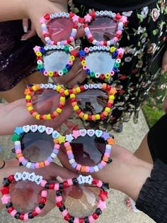 several people holding up colorful sunglasses with beads on the sides and one woman's hand