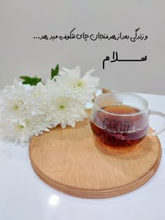 a cup of tea and some flowers on a wooden board with an arabic quote above it